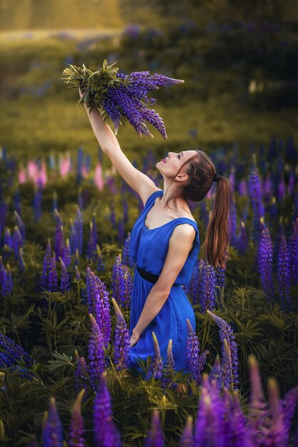 Foto menina com um buquê de flores, prado verde, flores roxas e rosa