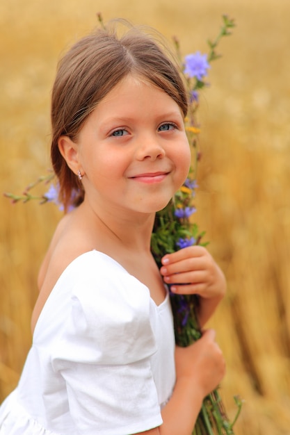 Menina com um buquê de flores silvestres no campo