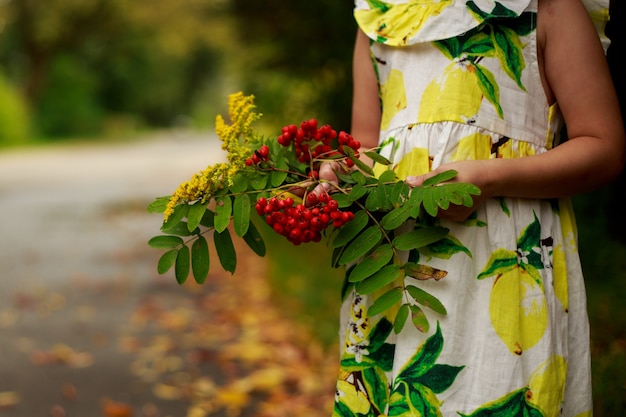 Menina com um buquê de folhas e flores