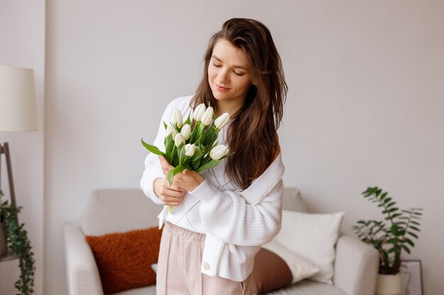 Menina com um buquê de tulipas na sala de estar