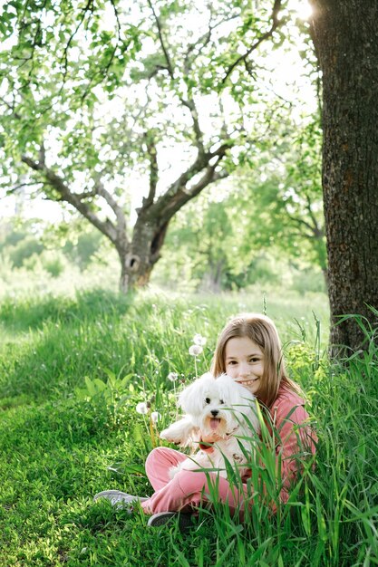 Menina com um cachorrinho maltês no verão ao ar livre