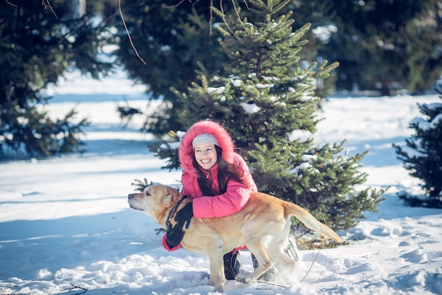 Menina com um cachorro Labrador cachorro brincando no inverno, diversão ao ar livre