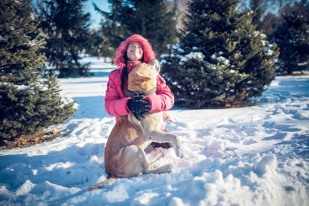 Menina com um cachorro Labrador cachorro brincando no inverno, diversão ao ar livre