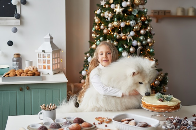 Menina com um cachorro perto da árvore de natal no natal