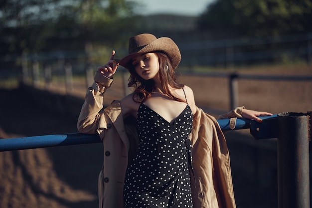 Menina com um chapéu de cowboy descansando na vila perto dos estábulos