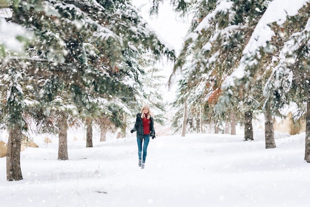 Menina com um chapéu de inverno elegante com uma estampa de leopardo se alegra na neve