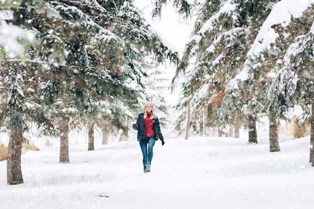 Menina com um chapéu de inverno elegante com uma estampa de leopardo se alegra na neve