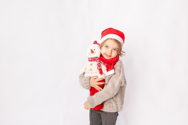 Menina com um chapéu de Papai Noel com um boneco de neve em um fundo branco, espaço para texto