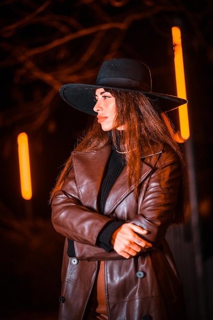 Menina com um chapéu em um retrato à noite em um pacote. Modelo morena caucasiana olhando para a câmera, estilo de vida e rua