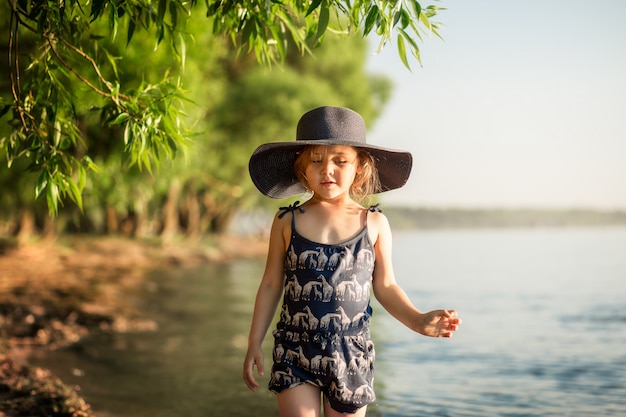 menina com um chapéu no rio no verão