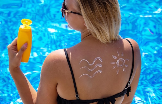 Menina com um desenho do sol nas costas com protetor solar. relaxamento na piscina. foco seletivo