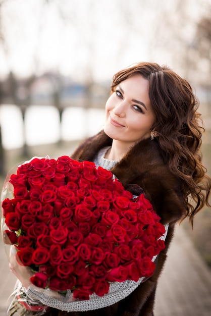 Menina com um grande buquê de rosas vermelhas. 101 rosas em um buquê