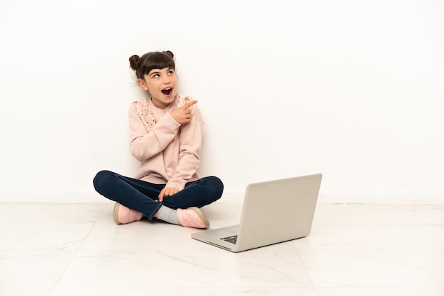 Menina com um laptop sentada no chão com a intenção de descobrir a solução enquanto levanta um dedo