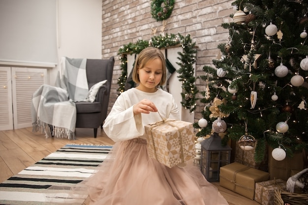 Menina com um presente na árvore de natal