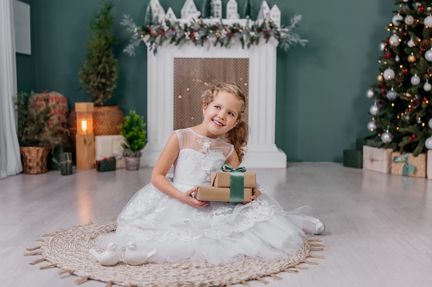 Menina com um presente nas mãos em um fundo no contexto das decorações de natal.