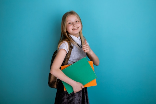 Menina com um vestido de escola em pé isolado o fundo azul.