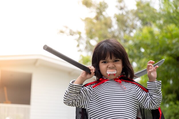 Foto menina com um vestido misterioso de halloween segurando uma foice no fundo branco