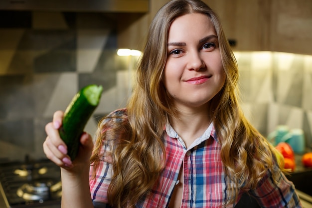 Menina com uma bela figura segurando vegetais