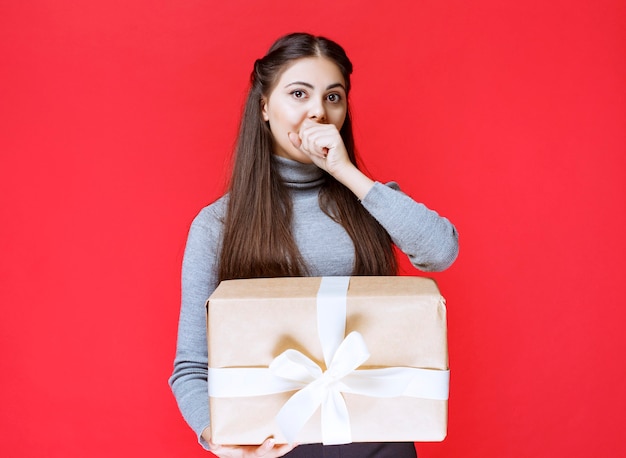 Menina com uma caixa de presente de papelão parece apavorada e cansada.