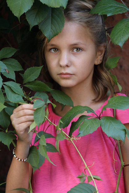 Menina com uma camiseta rosa com as folhas de uvas bravas. retrato de close-up