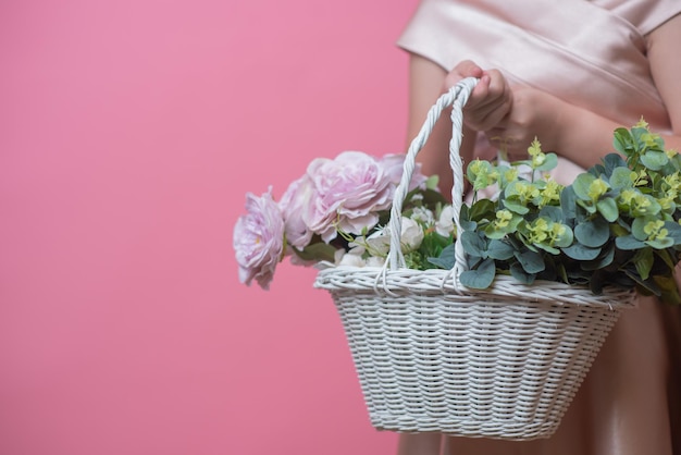 Menina com uma cesta de flores em um fundo rosa