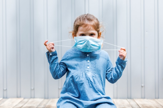 Foto menina com uma máscara médica nas mãos na rua