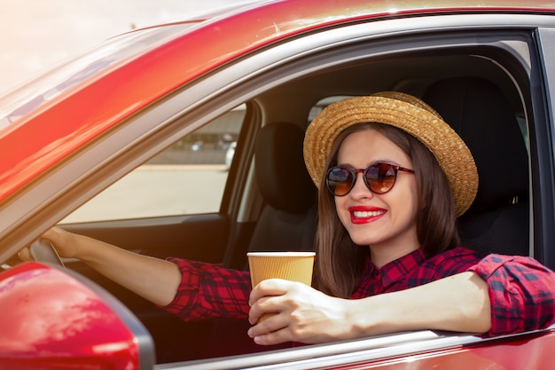 Menina com uma xícara de café no carro