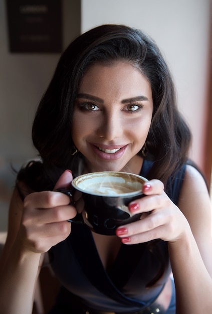 Menina com uma xícara de cappuccino em um café