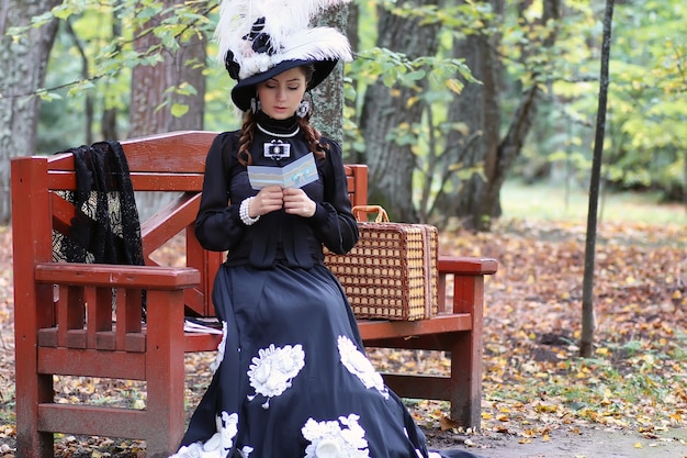 Menina com vestido retrô do século passado lendo carta no banco