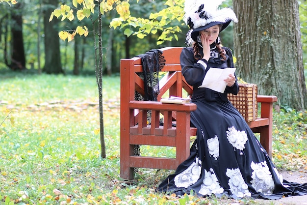 Menina com vestido retrô do século passado lendo carta no banco