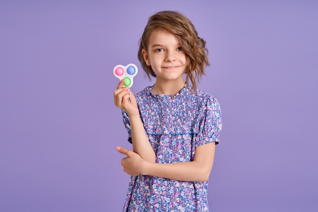 Menina com vestido roxo e um brinquedo popit em fundo roxo