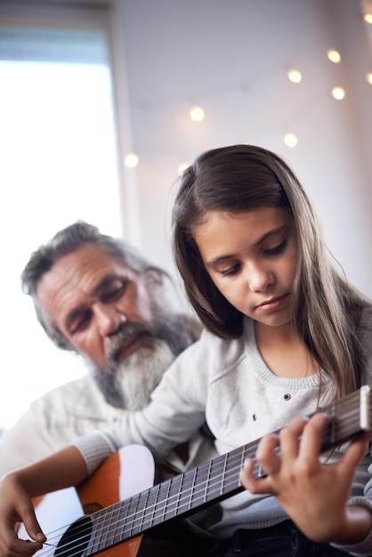 Menina com violão de avô e aprendendo a tocar educação musical e ajuda no desenvolvimento criativo Arte do músico e velho ajudando a criança a aprender foco e habilidade no instrumento musical