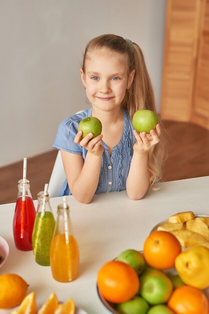 Menina come frutas em uma mesa cheia de comida