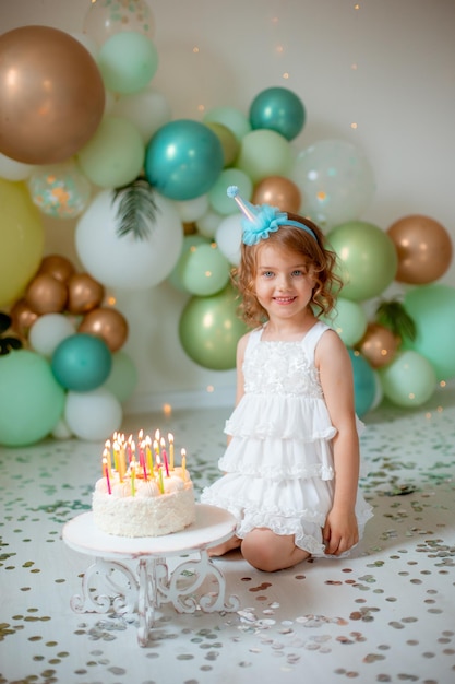 Menina comemora seu aniversário no contexto de balões soprando velas