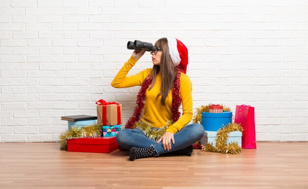 Menina comemorando as férias de natal e procurando algo à distância com binóculos