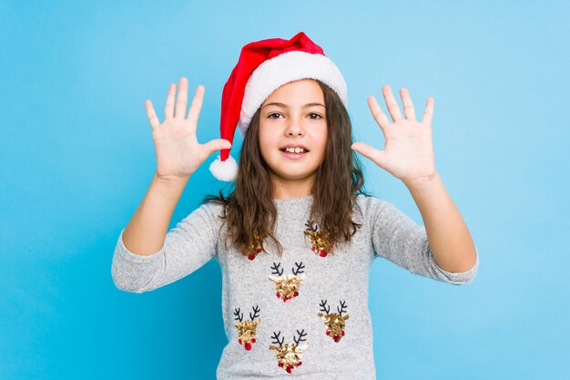 Menina comemorando o dia de Natal, mostrando o número dez com as mãos.