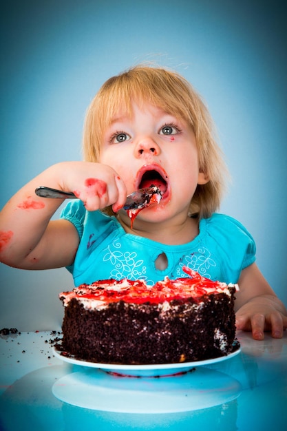 Menina comendo bolo em um fundo azul