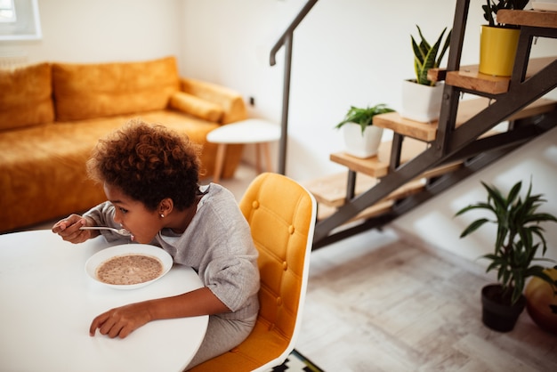 Menina comendo cereais no café da manhã.