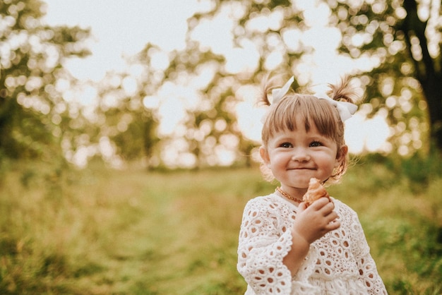 Menina comendo croissant na floresta