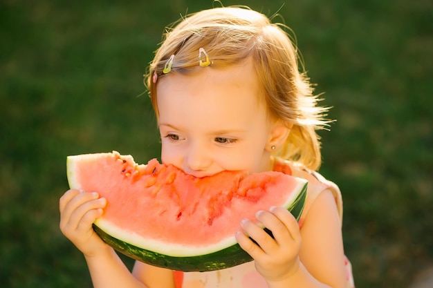 Menina comendo melancia vermelha ao ar livre