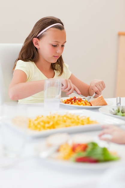 Menina comendo na mesa de jantar