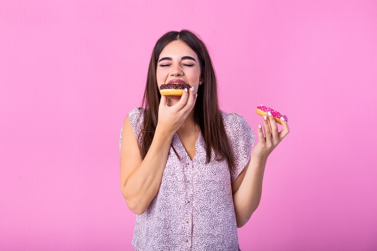 Foto menina comendo rosquinhas isoladas sobre rosa