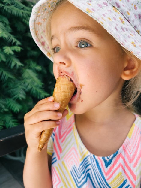 Menina comendo sorvete em um cone de waffle segurando com a mão