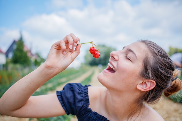 menina comendo um morango enquanto coleta morangos em um campo