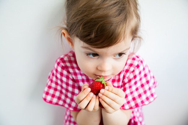 Menina comendo um morango grande