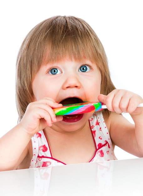 Menina comendo um pirulito pegajoso no fundo branco