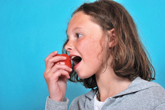 Foto menina comendo um tomate