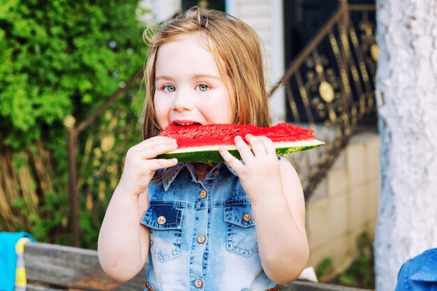 Menina comendo uma melancia no jardim