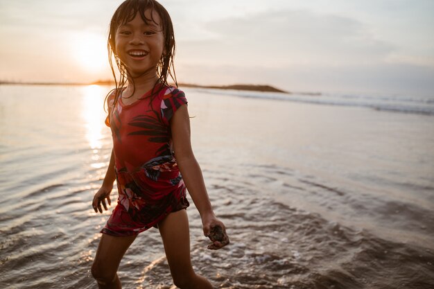 Menina correndo na praia enquanto brincava com água