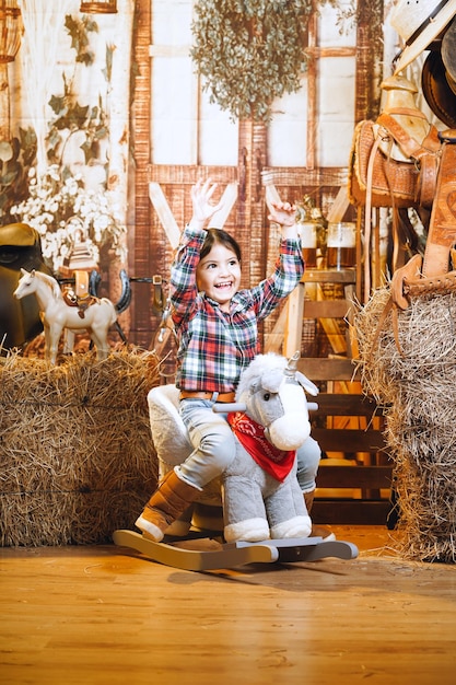 menina cowgirl no cavalo de brinquedo em conjunto de cowboy